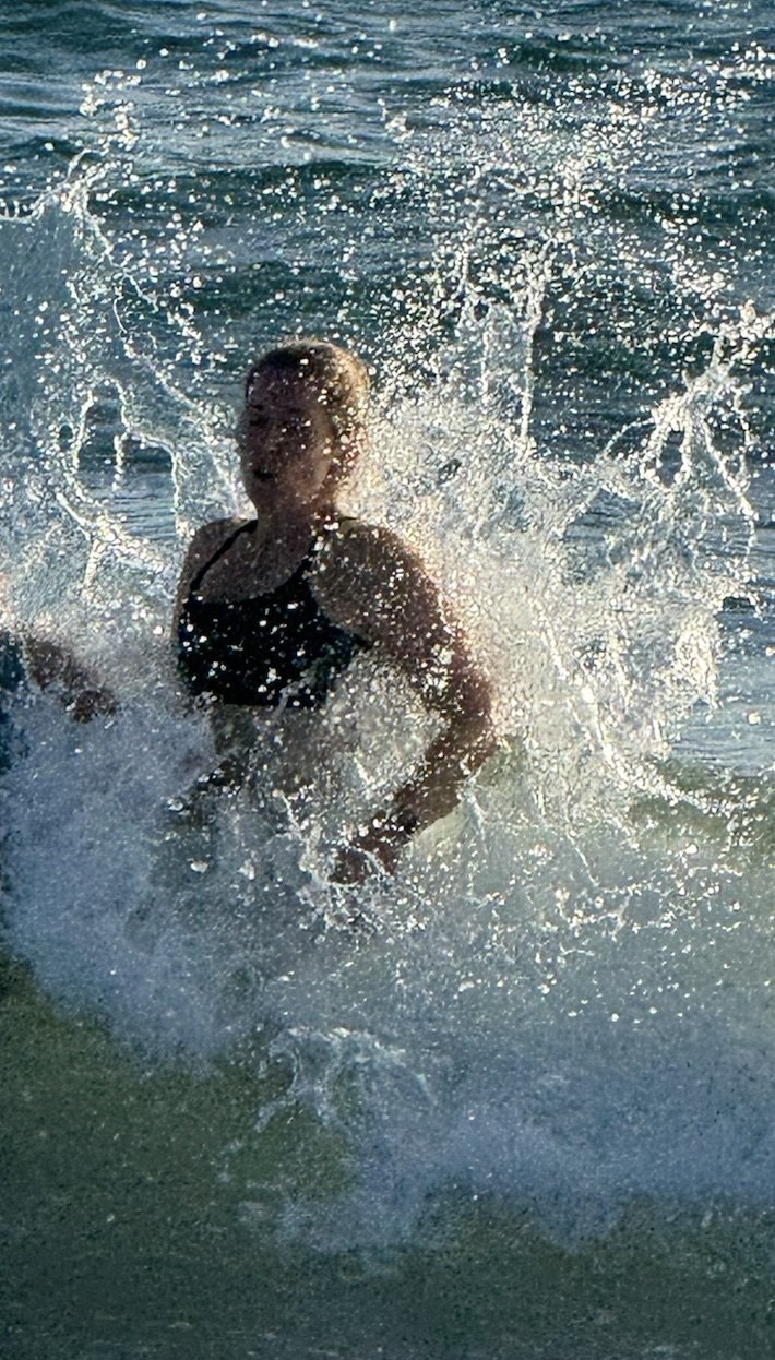 Jenn splashing in an ocean wave